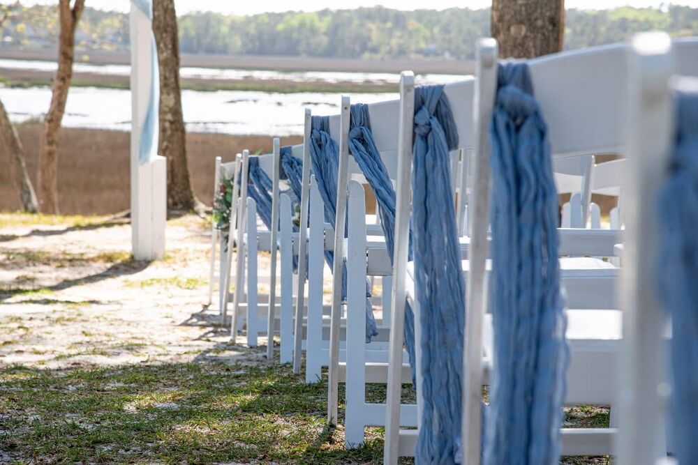 Ceremony aisle chairs with blue sashes, waterfront view