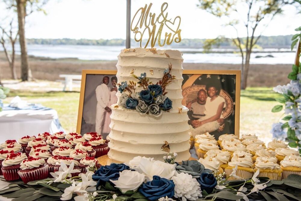 Mr. & Mrs. wedding cake with cupcakes and waterfront backdrop
